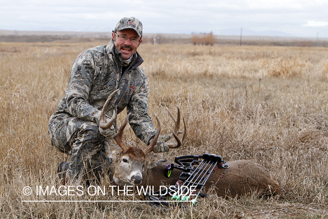 Bowhunter with downed white-tailed buck.