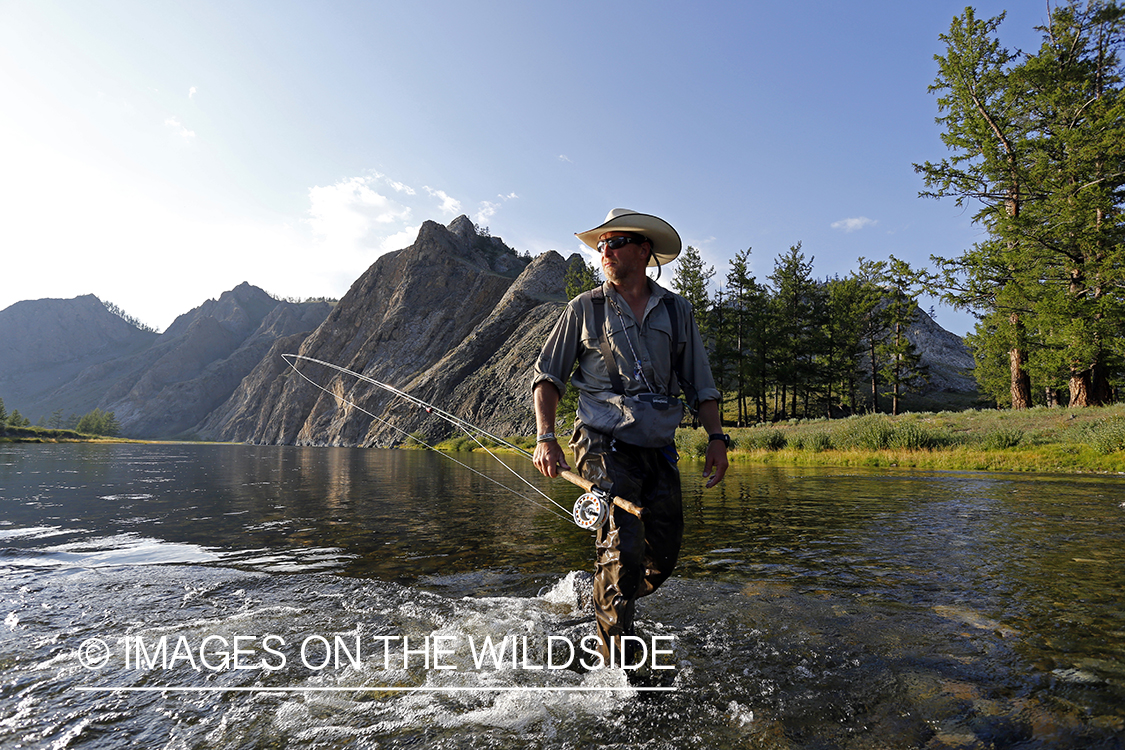Flyfisherman wading through Delger River, Mongolia.
