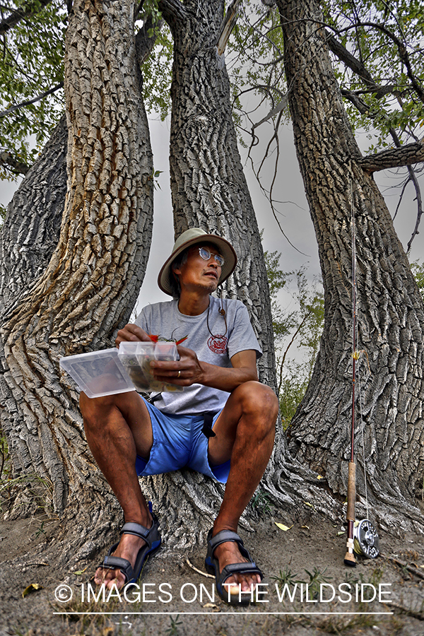 Flyfisherman checking flies along Delger River, Mongolia.