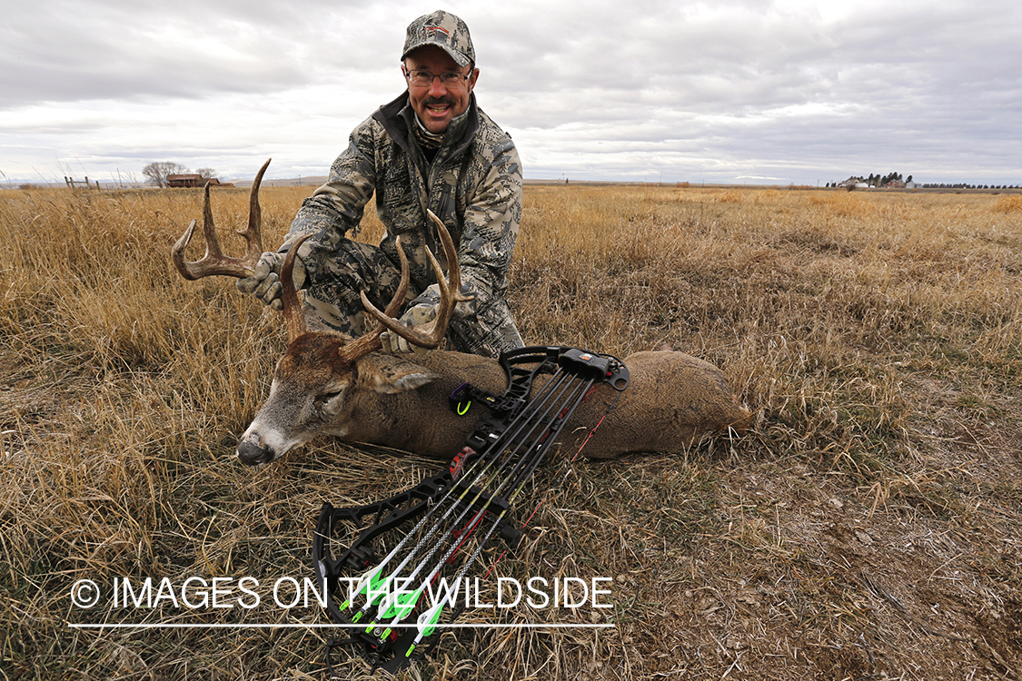 Bowhunter with downed white-tailed buck.