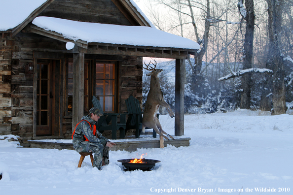 White-tailed deer hunte warming hands by campfire. 