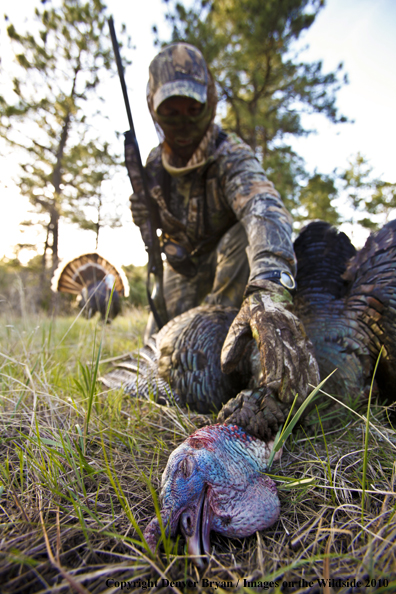 Hunter with bagged (Merriam's) turkey - decoy in bakcground