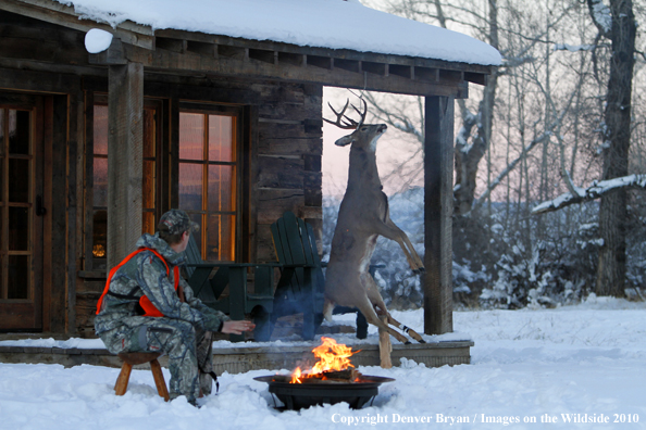 White-tailed deer hunter warming hands by campfire.