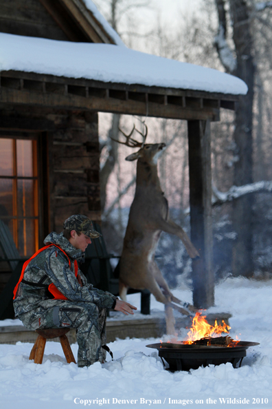 White-tailed deer hunter warming hands by campfire