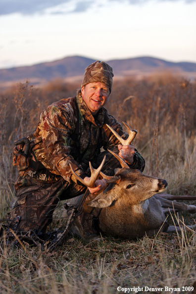 Bowhunter with whitetail buck kill.