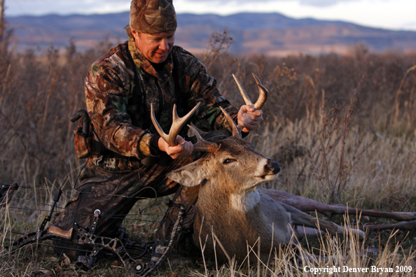 Bowhunter with whitetail buck kill.