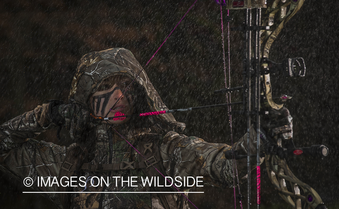Woman bowhunting in the rain.