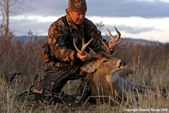 Bowhunter with whitetail buck kill.