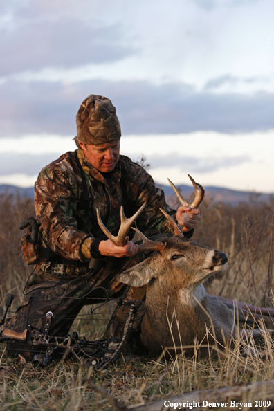 Bowhunter with whitetail buck kill.