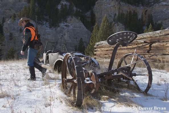 Big game hunter walking past old homestead.