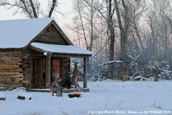 White-tailed deer hunter warming hands by campfire.