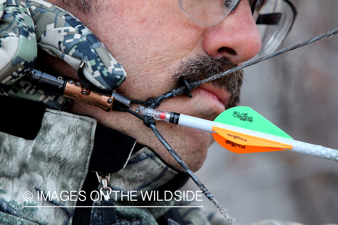 Bow hunter shooting arrow using arrow release attached to string.