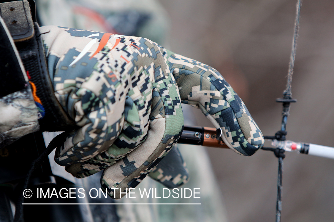 Bow hunter shooting arrow using arrow release attached to string.