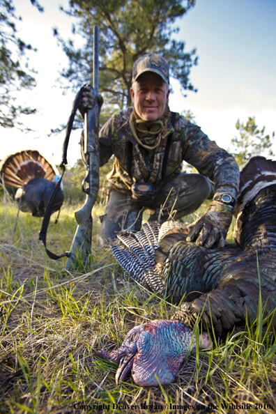 Hunter with bagged (Merriam's) turkey - decoy in bakcground