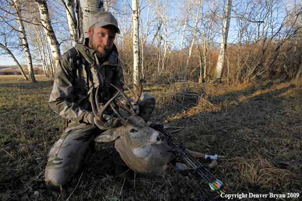 Bowhunter with bagged whitetail buck.