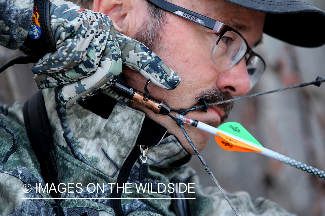 Bow hunter shooting arrow using arrow release attached to string.