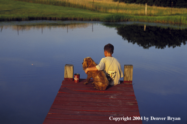 Boy spincast fishing with dog.