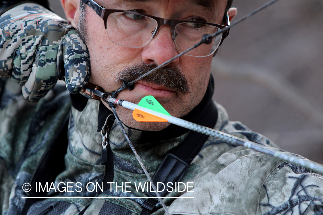 Bow hunter shooting arrow using arrow release attached to string.