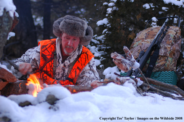 Big Game hunter starting fire in snow