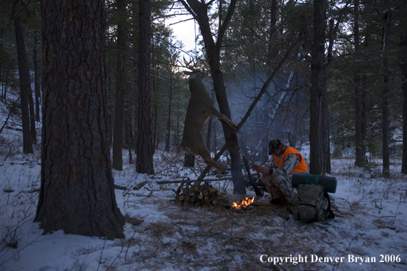 Deer hunter with bagged deer in camp in winter.  