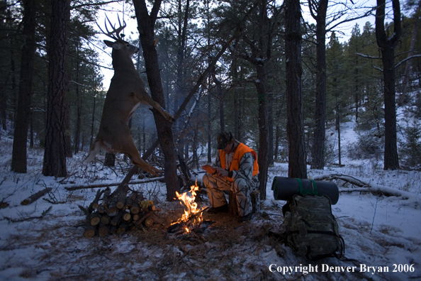 Deer hunter with bagged deer in camp in winter.  