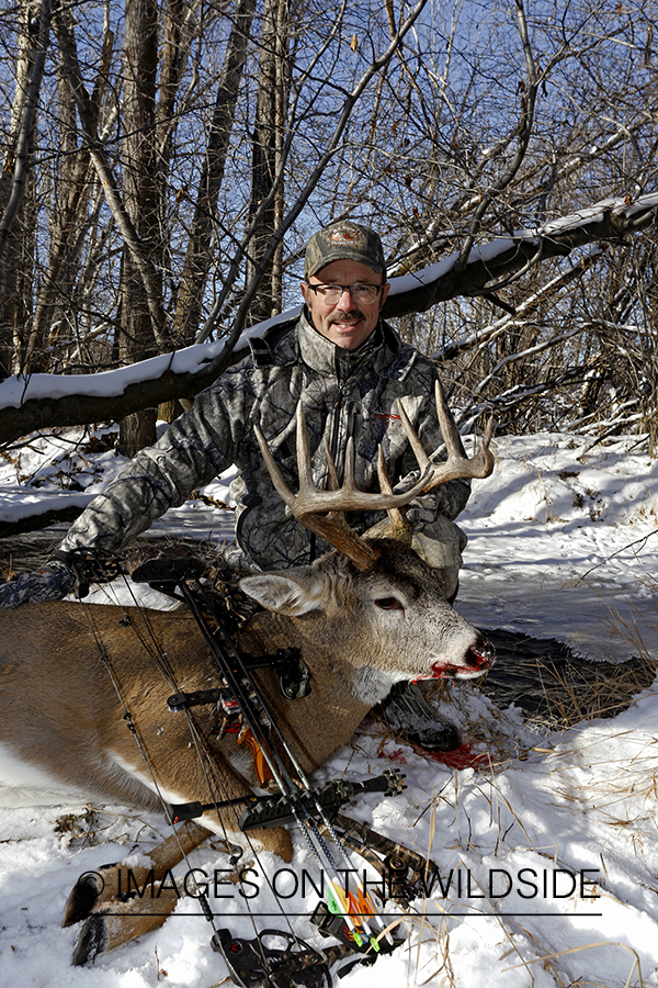 Bowhunter with downed white-tailed buck.
