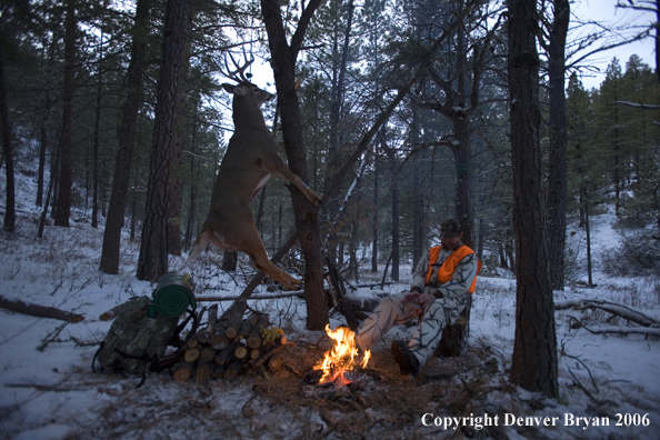 Deer hunter with bagged deer in camp in winter.  