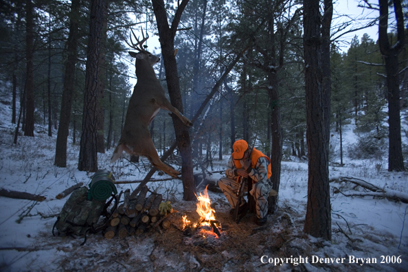 Deer hunter with bagged deer in camp in winter.  