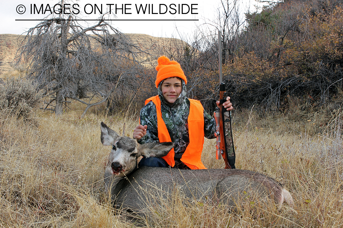 Young hunter with downed mule deer.