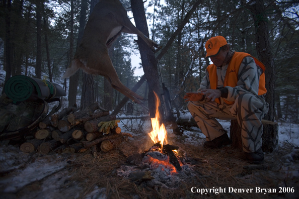 Deer hunter with bagged deer in camp in winter.  