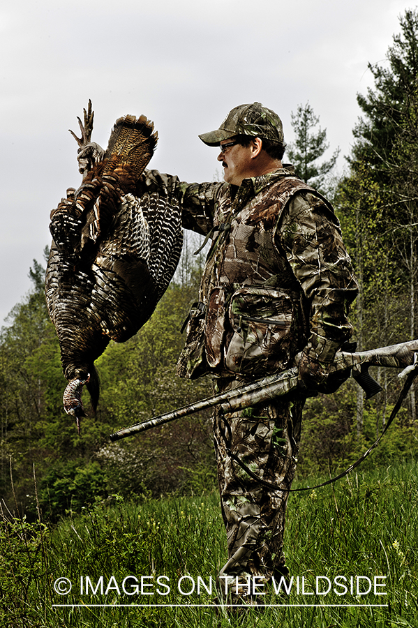 Turkey hunter with bagged turkey in field.