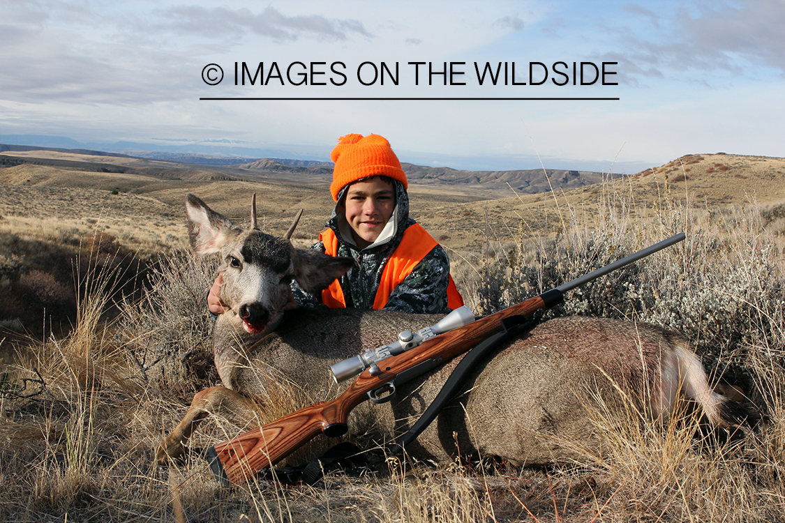 Young hunter with downed mule deer.