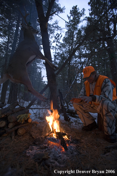 Deer hunter with bagged deer in camp in winter.  
