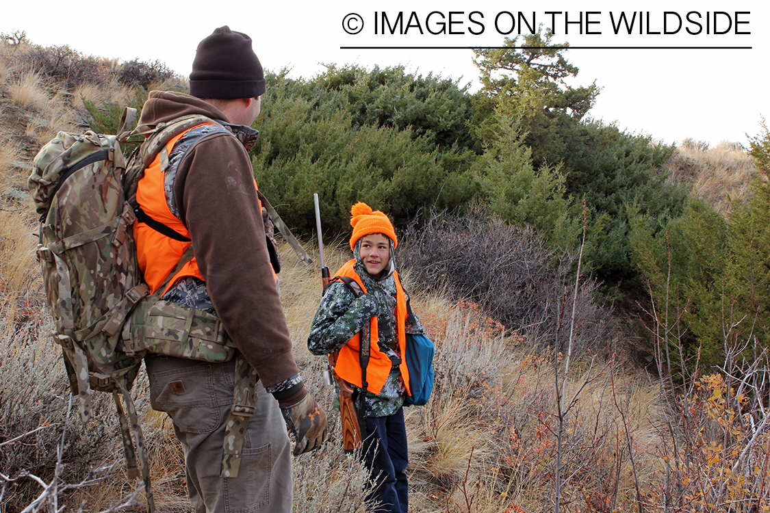 Adult and young hunter in field.